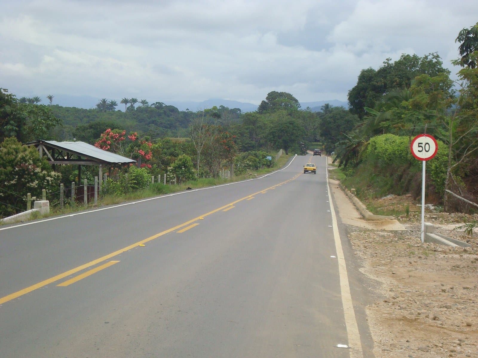 Carretera pavimentada de doble sentido entre vegetación selvática en la vía Marginal de la Selva, cerca de Florencia, Caquetá